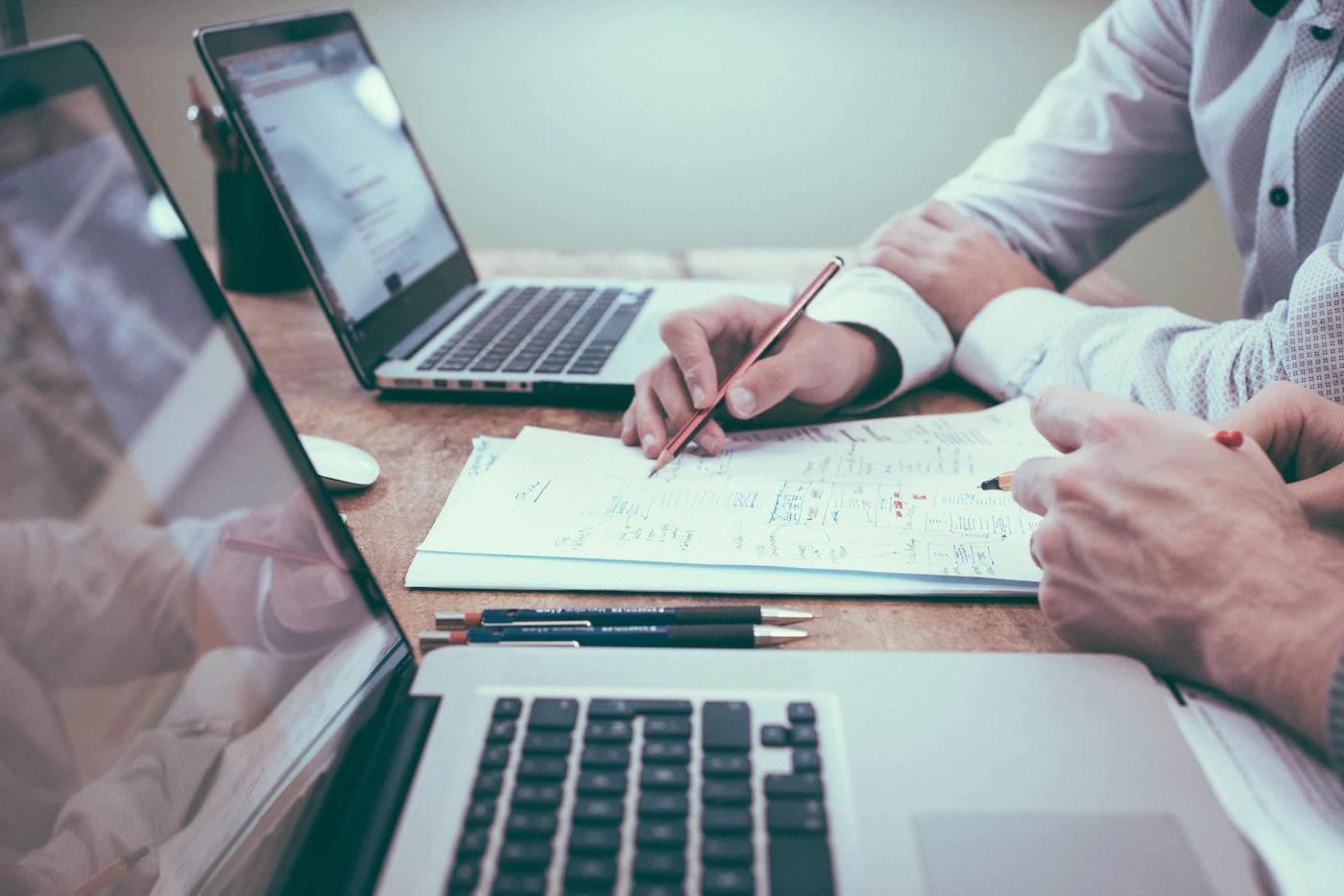 picture of 2 people discussing one with pencil in hand on a table with papers